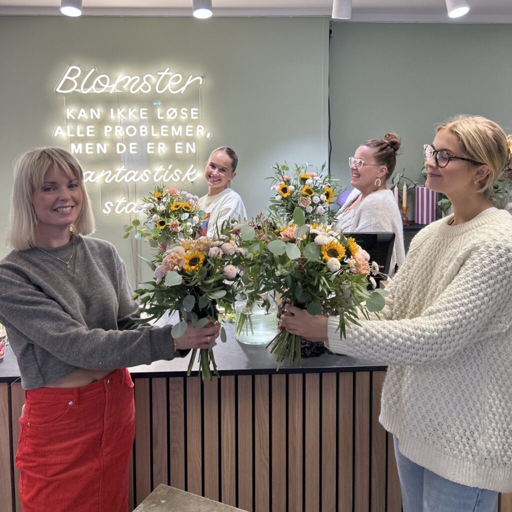 Ansatte i Plantedottir Blomsterbutikk som holder blomsterbuketter i Grimstad